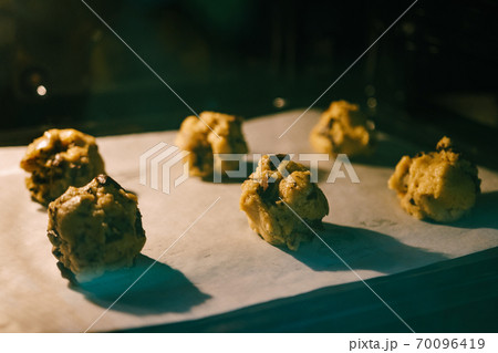 Balls of raw dough on baking paper in the oven on a baking tray. 70096419
