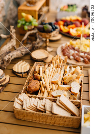 Wicker bread and cereal tray with sliced loaf, bread sticks and cookies on a wooden holiday table. Wicker bread and cereal tray with sliced loaf, bread sticks and cookies on a wooden holiday table. 70096502