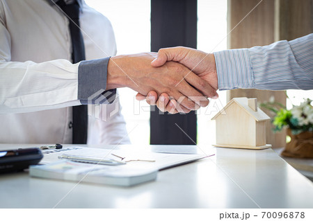 Both businessmen shake hand to congratulate them on their successful signing of a contract with a home insurance agent, housing purchase and insurance Concept. Both businessmen shake hand to congratulate them on their successful signing of a contract with a home insurance agent, housing purchase and insurance Concept. 70096878
