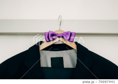 Jacket with striped lining and purple bow tie on a hanger. 70097441