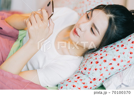 Woman using smartphone on bed Woman using smartphone on bed 70100370