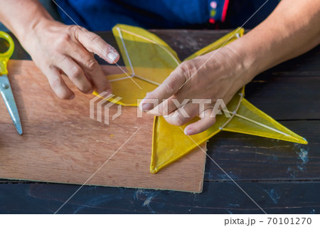 Eldery woman making and build star-shaped kite or thai name Chula kite for sale at local market. Selective focus on .left hand finger.. 70101270