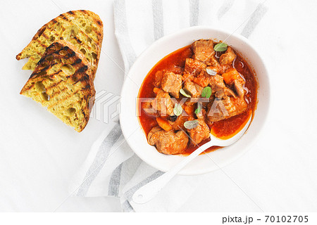 Slow cooked pork with vegetables, carrots, onions and ripe tomatoes with sweet peas and bay leaves in a plate. View from above. Comfortable homemade food 70102705