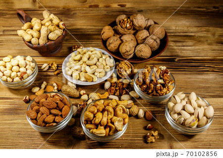 Assortment of nuts on wooden table. Almond, hazelnut, pistachio, peanut, walnut and cashew in small bowls. Healthy eating concept Assortment of nuts on wooden table. Almond, hazelnut, pistachio, peanut, walnut and cashew in small bowls. Healthy eating concept 70102856