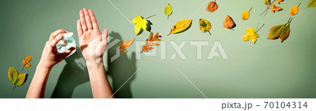Applying sanitizer gel with autumn leaves Applying sanitizer gel with autumn leaves 70104314
