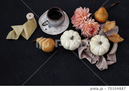 Autumn still life composition. Cup of coffee, pear fruit and white pumpkins with pink dahlia flowers on black table background. Moody fall, Thanksgiving design. Flat lay, top view. 70104887
