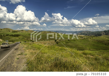 Turn on the road, located high in the mountains of the Gegham range against the blue sky covered with Cumulus clouds in Armenia. Turn on the road, located high in the mountains of the Gegham range against the blue sky covered with Cumulus clouds in Armenia. 70105310