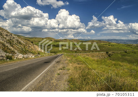 A road in the mountains of the Gegham range against a blue sky covered with clouds in Armenia 70105311
