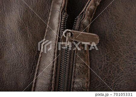 Close-up shot of a zip fastener on a brown belt. 70105331