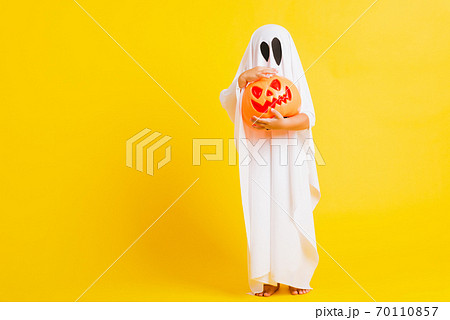 little cute child with white dressed costume halloween ghost scary he holding orange pumpkin ghost on hand little cute child with white dressed costume halloween ghost scary he holding orange pumpkin ghost on hand 70110857