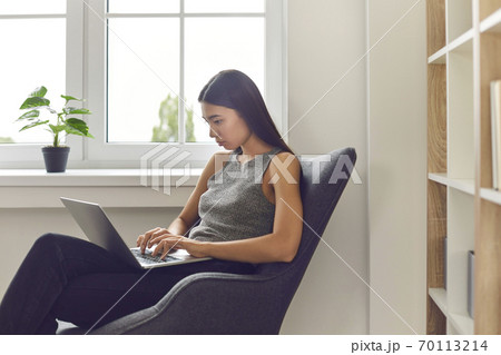 Asian woman office worker sitting in armchair and working on laptop 70113214