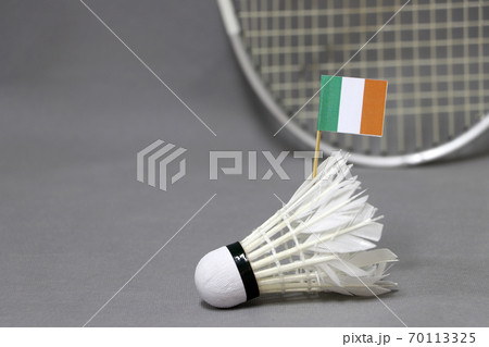 Mini Ireland flag stick on the white shuttlecock on the grey background and out focus racket. 70113325