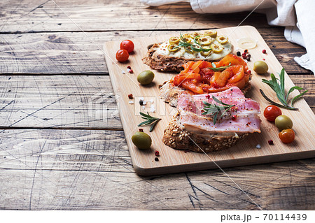 Wholegrain bread sandwiches with cream cheese, bacon and olives canned peppers with tomato on wooden background. Copy space. 70114439