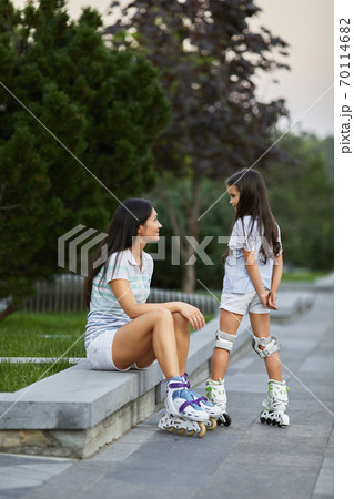 happy little child girl and her mother are wearing roller skates happy little child girl and her mother are wearing roller skates 70114682