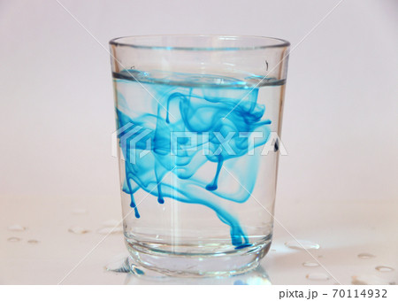 Blue color free movement in a glass of water, on white background. 70114932
