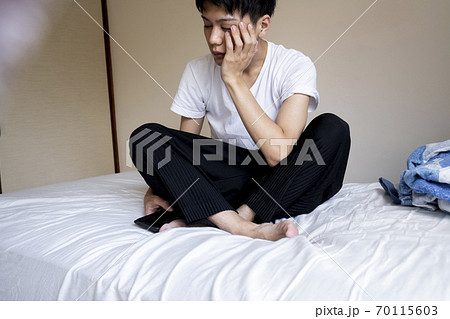 ベッドに座る男性の写真素材 [70115603] - PIXTA