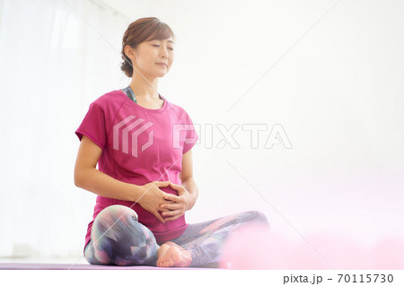 胡座をかいてお腹を触る妊婦 70115730
