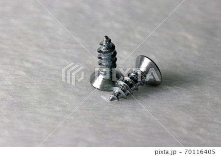 Two metal screw put on the white fabric floor.  70116405