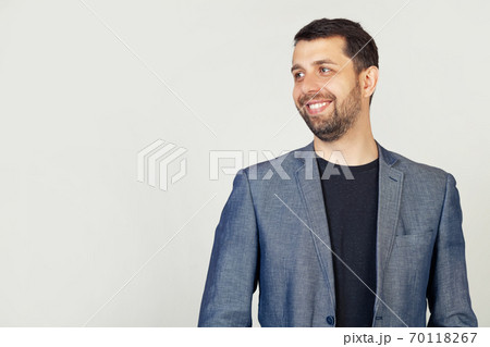 Closeup of a handsome bearded guy in a jacket standing in profile, looking to the side, posing for a Closeup of a handsome bearded guy in a jacket standing in profile, looking to the side, posing for a 70118267