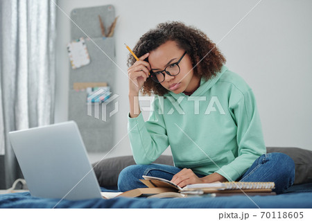 Young student in jeans and hoodie trying to concentrate in front of laptop Young student in jeans and hoodie trying to concentrate in front of laptop 70118605