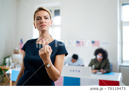 Portrait of confident woman voter showing middle finger in polling place, usa elections concept. Portrait of confident woman voter showing middle finger in polling place, usa elections concept. 70119473
