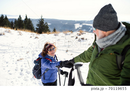 Senior couple with nordic walking poles hiking in snow-covered winter nature. Senior couple with nordic walking poles hiking in snow-covered winter nature. 70119655