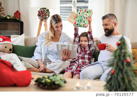 Family with small daughter indoors at home at Christmas, having video call. 70120577