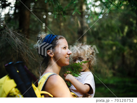 Side view of mother with small daughter outdoors in summer nature, resting. 70120752