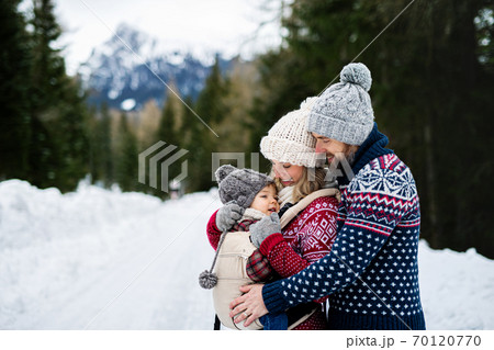 Father and mother with small child in winter nature, standing in the snow. 70120770