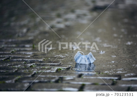 Used face mask in puddle during rain 70123531