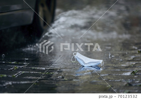 Used face mask in puddle during rain 70123532