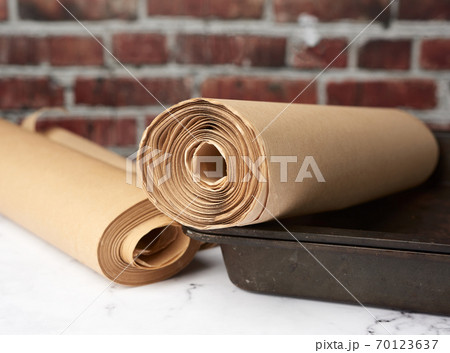 metal pan and rolls of brown parchment paper on a white table metal pan and rolls of brown parchment paper on a white table 70123637