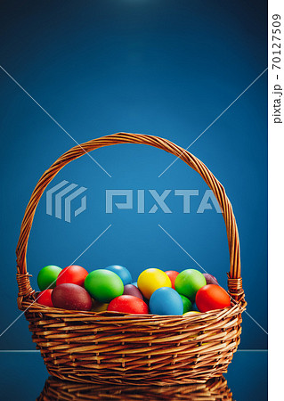 Easter color eggs in festive gift basket, blue background 70127509