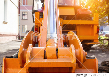rear hydraulic bucket with a pump on a loader that stands in the courtyard of the house. Repair work, industry, pipe laying rear hydraulic bucket with a pump on a loader that stands in the courtyard of the house. Repair work, industry, pipe laying 70128056