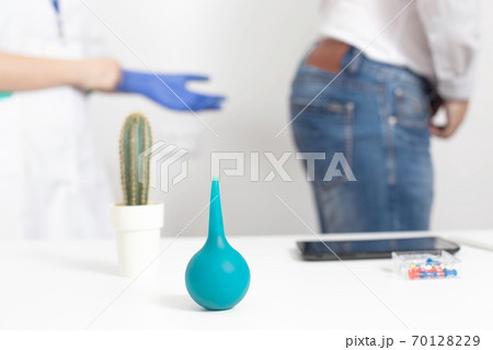 Doctor proctologist puts on medical gloves for a digital examination of the patient s rectum for diseases of the hemorrhoids and anal fissures, background 70128229