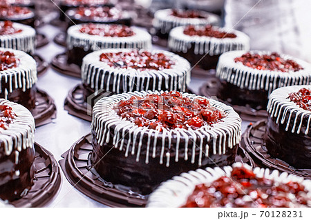 Many beautiful and delicious chocolate cakes with fresh cherry and cream. Confectionery production for the manufacture of cakes and pastries, torte, background 70128231