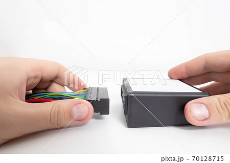 A man connects electrical wiring to an electronic engine control unit that is responsible for idling and adjusting the ignition, copy space A man connects electrical wiring to an electronic engine control unit that is responsible for idling and adjusting the ignition, copy space 70128715