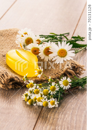 Yellow soap on sackcloth with bouquet of fresh chamomiles on wooden boards Yellow soap on sackcloth with bouquet of fresh chamomiles on wooden boards 70131126