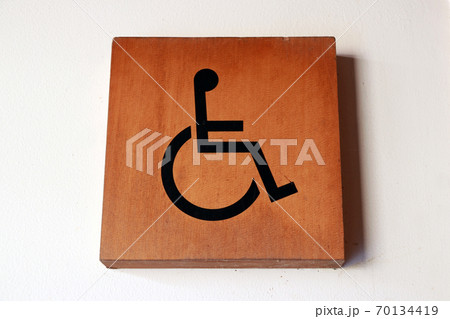 Wooden handicapped mark on the wall in front of the Bathroom disabled. 70134419