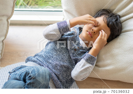 An Asian boy has eyestrain due to excessive playing with mobile phones. 70136032