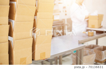 A worker at a dairy plant puts butter and glazed curds into boxes. Production of dairy products in production, export A worker at a dairy plant puts butter and glazed curds into boxes. Production of dairy products in production, export 70136631