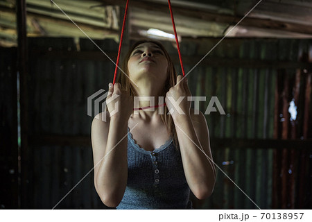 woman look at gallows and hold red rope noose 70138957