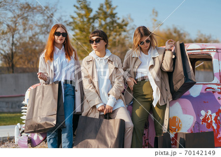 Young women posing near an old decorated car Young women posing near an old decorated car 70142149