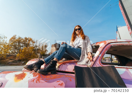 Young woman sits on an old decorated car Young woman sits on an old decorated car 70142150
