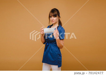 A girl doctor stands in a medical mask, isolated on a gray background. A girl doctor stands in a medical mask, isolated on a gray background. 70142477