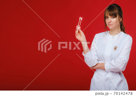 Beautiful girl doctor with a tuning fork stands 70142478