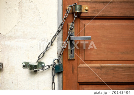 Closed door with a lock hanging over it 70143404