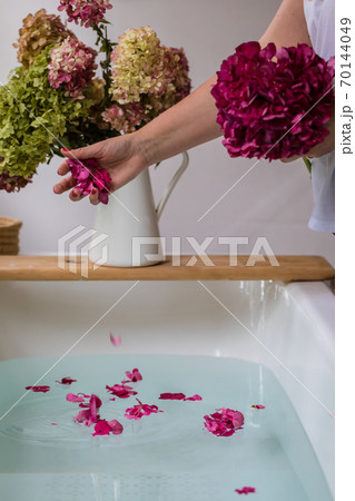 Partial view of woman throwing hydrangea petals in bath, selective focus Partial view of woman throwing hydrangea petals in bath, selective focus 70144049