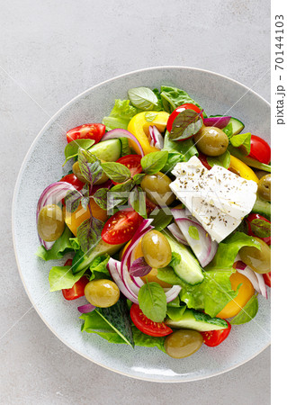 Greek salad. Fresh vegetable salad of cucumbers, tomatoes, olives, onion, bell pepper, feta cheese, lettuce and herbs and dressed with salt, pepper and olive oil. Horiatiki salad Greek salad. Fresh vegetable salad of cucumbers, tomatoes, olives, onion, bell pepper, feta cheese, lettuce and herbs and dressed with salt, pepper and olive oil. Horiatiki salad 70144103