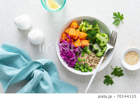 Vegetarian quinoa and broccoli lunch Buddha bowl with baked butternut squash or pumpkin, green peas and red cabbage, top down view 70144135